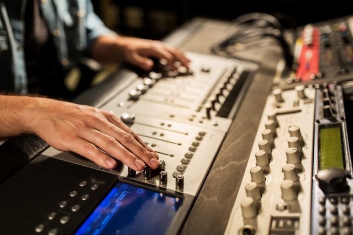 man using mixing console in music recording studio